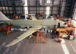 An airplane under construction inside a large plane hangar.